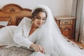 Beautiful young bride in a white peignoir lying on the bed in her bedroom Royalty Free Stock Photo