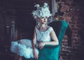 Beautiful young brunette bride wearing white dress and wreath of flowers sits on a chair. Royalty Free Stock Photo