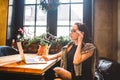 Beautiful young brunette business woman wearing glasses and sweater uses laptop to print text on keyboard. In coffee house, sittin Royalty Free Stock Photo