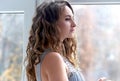 A beautiful young brunette Caucasian portrait looks out the window Royalty Free Stock Photo