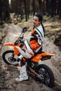 Beautiful young female racer riding motocross bike on a trail of sand in the woods Royalty Free Stock Photo