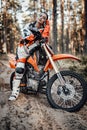 Beautiful young female racer riding motocross bike on a trail of sand in the woods Royalty Free Stock Photo