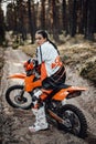 Beautiful young female racer riding motocross bike on a trail of sand in the woods Royalty Free Stock Photo