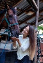 Beautiful young girl looks after her horse in the stable.