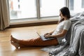 Beautiful young brunette girl working on a laptop, sitting on the floor near the bed by the panoramic window with a beautiful view Royalty Free Stock Photo