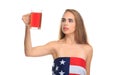 A girl, wrapped in a American flag, holds a glass of beer and looks closely at it. Isolated on white. Royalty Free Stock Photo