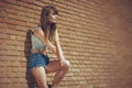 Beautiful young brunette in jeans clothes posing outdoor near red brick wall Royalty Free Stock Photo