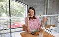 Beautiful young brunette talking on a cell phone in restaurant while eating. Multitasking, positive concept