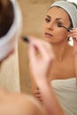 Beautiful young woman applying mascara in front of mirror Royalty Free Stock Photo