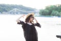 Beautiful young brunette woman in black dress, black sunglasses and straw hat walking on the sand on the beach and Royalty Free Stock Photo