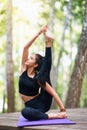 Beautiful young brunette woman in black sportswear practices yoga, doing Surya Yantrasana exercise Royalty Free Stock Photo