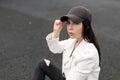 Beautiful young brunette woman with brown eyes in a stylish American baseball cap in a stylish leather white jacket in torn jeans