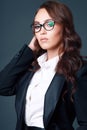 This is a beautiful young brunette woman in a business classic suit and glasses. Studio portrait of a business woman Royalty Free Stock Photo