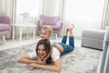 Beautiful young brunette woman with cute baby girl on her shoulders wearing jeans and white t-shirts lying on the floor Royalty Free Stock Photo