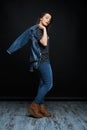 Beautiful young brunette woman in denim clothes posing against dark studio background. Royalty Free Stock Photo