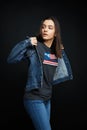 Beautiful young brunette woman in denim clothes posing against dark studio background. Royalty Free Stock Photo