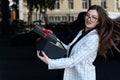 Beautiful young brunette woman with gift box in her hands. Woman in business suit and glasses opens gift box Royalty Free Stock Photo