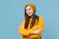 Beautiful young brunette woman girl in yellow sweater and hat posing isolated on blue background studio portrait. People Royalty Free Stock Photo