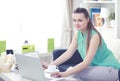 Beautiful young brunette woman at home sitting on sofa or settee using her laptop computer Royalty Free Stock Photo