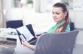 Beautiful young brunette woman at home sitting on sofa or settee using her laptop computer Royalty Free Stock Photo