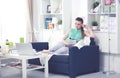 Beautiful young brunette woman at home sitting on sofa or settee using her laptop computer Royalty Free Stock Photo