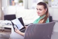 Beautiful young brunette woman at home sitting on sofa or settee using her laptop computer Royalty Free Stock Photo