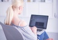 Beautiful young brunette woman at home sitting on sofa or settee using her laptop computer Royalty Free Stock Photo