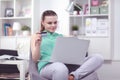 Beautiful young brunette woman at home sitting on sofa or settee using her laptop computer Royalty Free Stock Photo