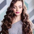 Beautiful young brunette woman with long curly hair and evening makeup, fashion beauty portrait Royalty Free Stock Photo