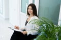 Beautiful young brunette woman patient filling out a form before doctor`s appointment at clinic, healthcare and medical concept Royalty Free Stock Photo