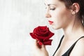 Beautiful young brunette Woman with red lips and red rose in her hand near the face as a symbol of love and care on St Royalty Free Stock Photo