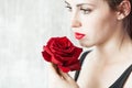 Beautiful young brunette Woman with red lips and red rose in her hand near the face as a symbol of love and care on St. Valentine Royalty Free Stock Photo
