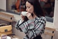 Beautiful young brunette woman sipping cappuccino outside the coffee place. Rest in city. Royalty Free Stock Photo