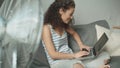 Pretty woman relaxing on sofa using her laptop at home in the living room.