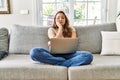 Beautiful young brunette woman sitting on the sofa using computer laptop at home thinking looking tired and bored with depression Royalty Free Stock Photo