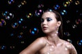 Beautiful young brunette woman with soap bubbles on black background Royalty Free Stock Photo