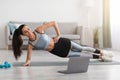 Beautiful woman exercising with dumbbells at home, using laptop Royalty Free Stock Photo