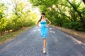 Beautiful young brunette woman walking on empty road at summ