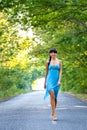 Beautiful young brunette woman walking on empty road at summ