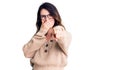 Beautiful young brunette woman wearing casual clothes and glasses laughing at you, pointing finger to the camera with hand over Royalty Free Stock Photo