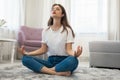 Beautiful young brunette woman wearing jeans and white t-shirt sitting on the floor in asana yoga position in bright