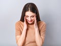 Beautiful young business toothy laughing woman looking down with happy smile holding the hands the head on blue grey background Royalty Free Stock Photo