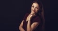 Beautiful young business toothy smiling woman thinking and looking happy in burgundy blouse and with red lipstick on dark shadow Royalty Free Stock Photo