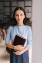 Beautiful young business woman holding file folder while standing near window in modern office room. Royalty Free Stock Photo