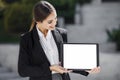 Beautiful young business woman is holding a tablet pc, with a blank screen, vertically, while smiling Royalty Free Stock Photo