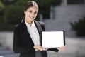 Beautiful young business woman is holding a tablet pc, with a blank screen, vertically, while smiling Royalty Free Stock Photo