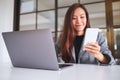 A young business woman holding and using mobile phone with laptop computer on wooden table Royalty Free Stock Photo