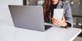 A young business woman holding and using mobile phone with laptop computer on wooden table Royalty Free Stock Photo