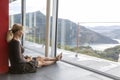 Beautiful young business woman pausing at her home, sitting on the ground while looking out the window, in the background you can Royalty Free Stock Photo