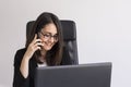 Beautiful young Business woman using his laptop and talking on her mobile phone in the office. Business Concept. Lifestyle Royalty Free Stock Photo